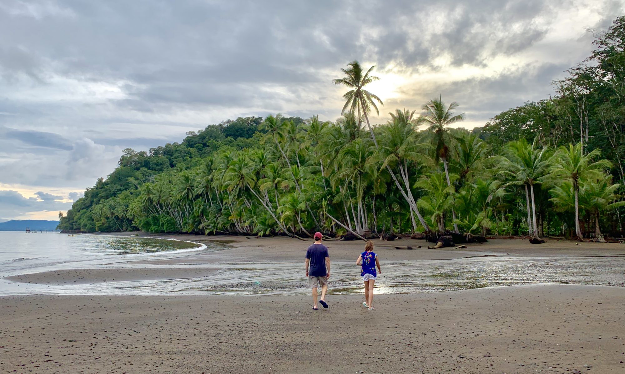 two travelers walking at the beach with palm trees