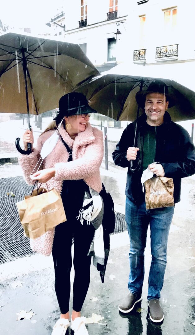 A couple holding umbrellas and bags in rain