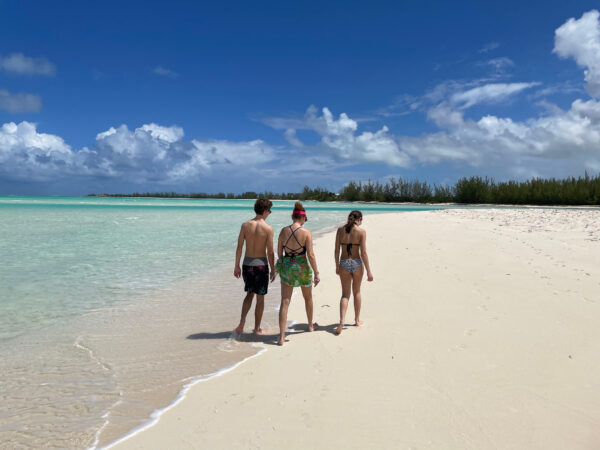 three people walking on a beach
